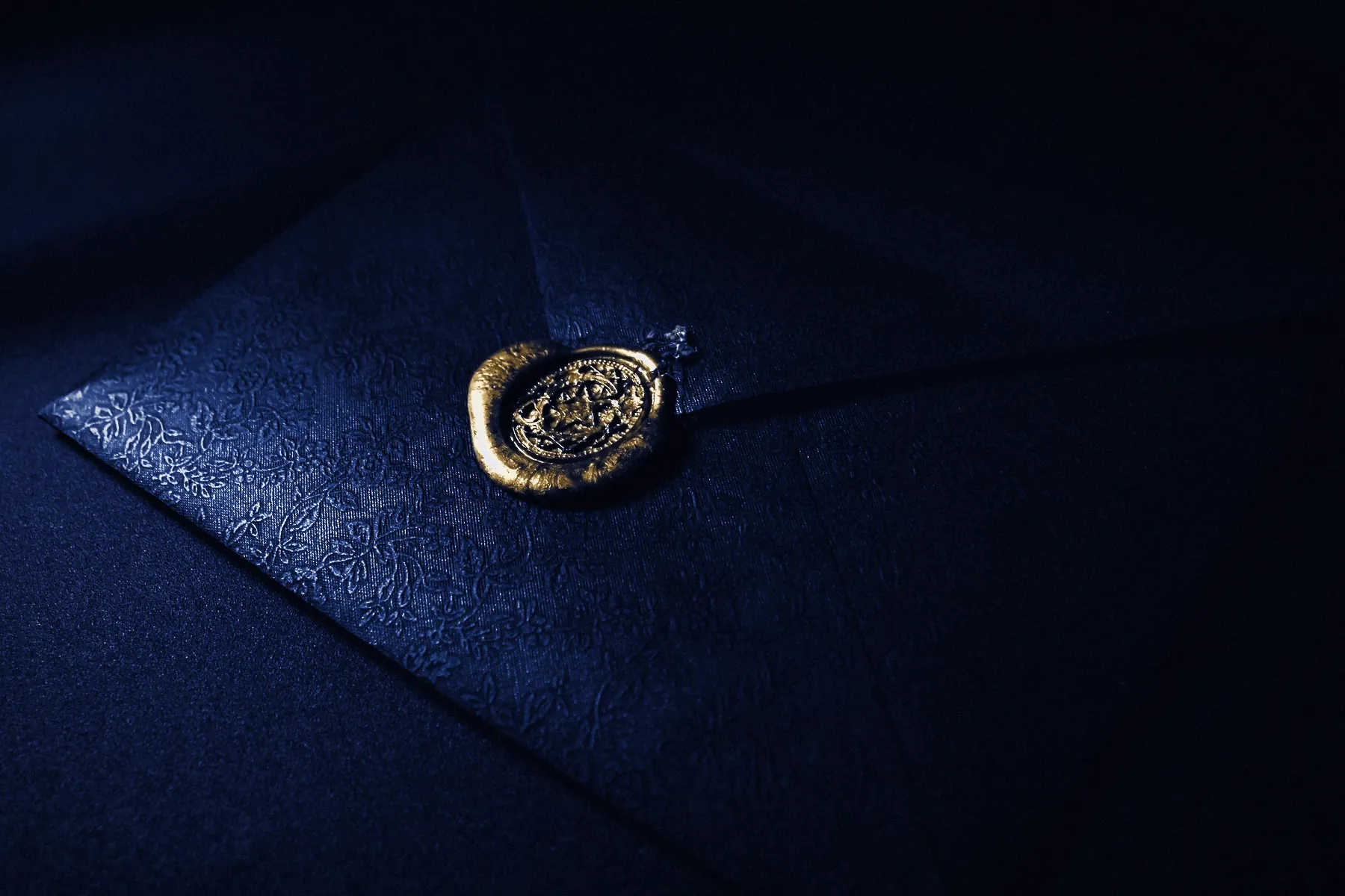 A navy envelope closed with a gold wax seal